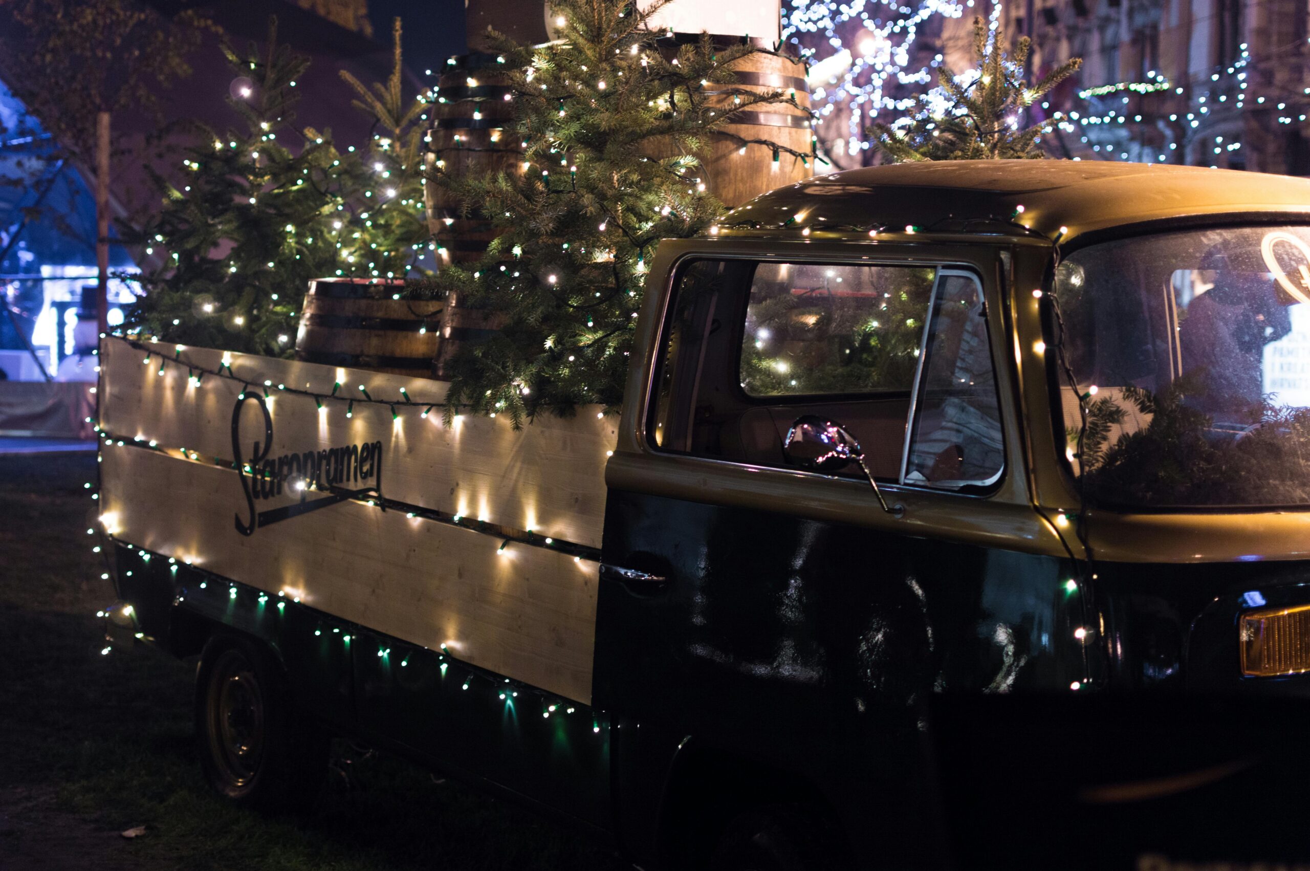 Vintage truck decorated with festive holiday lights and loaded with Christmas trees and rustic barrels at a local San Antonio holiday market. Perfect holiday vibe showcasing unique charm and community spirit in the Hill Country.